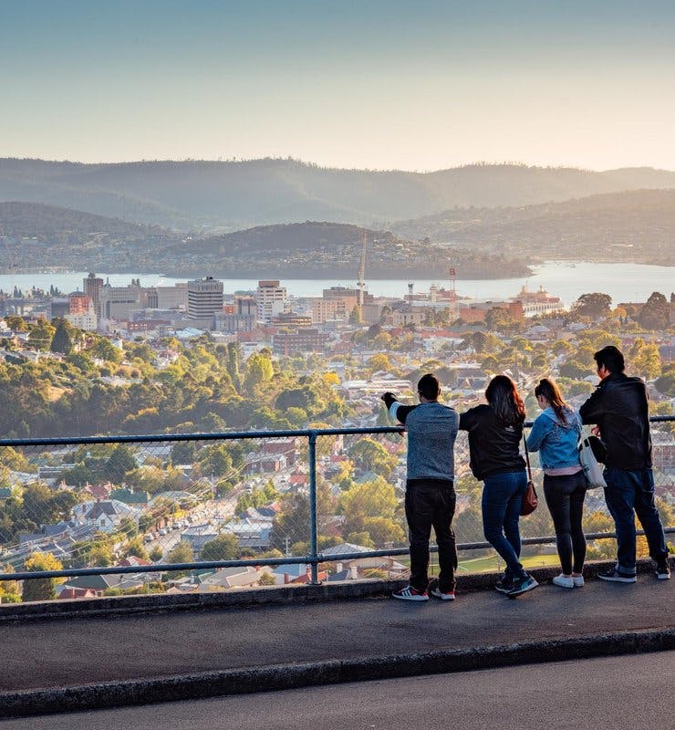 Three people on a viewing platform looking out over a city
